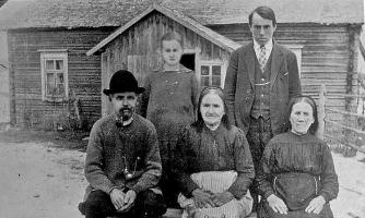 Taustalla on Peltolan tupa ja seisomassa nuorempi Simo Suuronen s.1889. Vierellään on talon miniä Anna o.s. Vanhapelto s.1890. Vanhempi Simo Suuronen s.1855 polttelee vakaasti piippuaan ja vierellä istuu emäntä Katriina s.1855. Penkin päässä on nuoremman Simon anoppi. Kuva lienee keväältä 1911, sillä nuorenparin esikoinen syntyi seitsemästoista kesäkuuta.