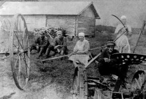 Heinät on tehty Harjussa! Maria s.1892 tutkii vielä viikatteensa kuntoa. Lyydia s.1901 on istahtanut niin kuin vas August s.1901 ja Antti s.1898 taustalla ja vanha Simo s.1855 niittokoneen takana. Maria kävi myös Amerikassa.