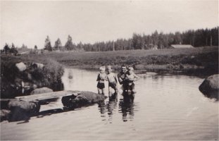 Julius Myllynen ja hänen lapsensa Erkki, Laina ja Aarne Marjakydön uimarannalla. Taustalla Mattilan talo Koskelan kylässä.  (Päivi Rämö)