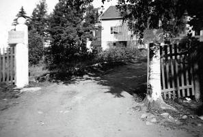 Pappilan portilla. Sinne eivät kaikki päässet sisälle sillä pappila oli jatkosodan syksyn aikana jonkin aikaa sotavankileirinä kuten portin pielessä olevassa kyltissä lukee. Uusi pappila 1941 (Leena Räsänen)