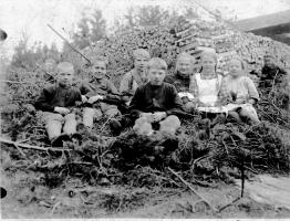 Vanhakylän koulun oppilaita koulun pihalla keväällä polttopuutalkoiden jälkeen, lapset istuvat havupatjan päällä. Vanhakylän koulu 1920-luku 1921?(Tapio Ruti)